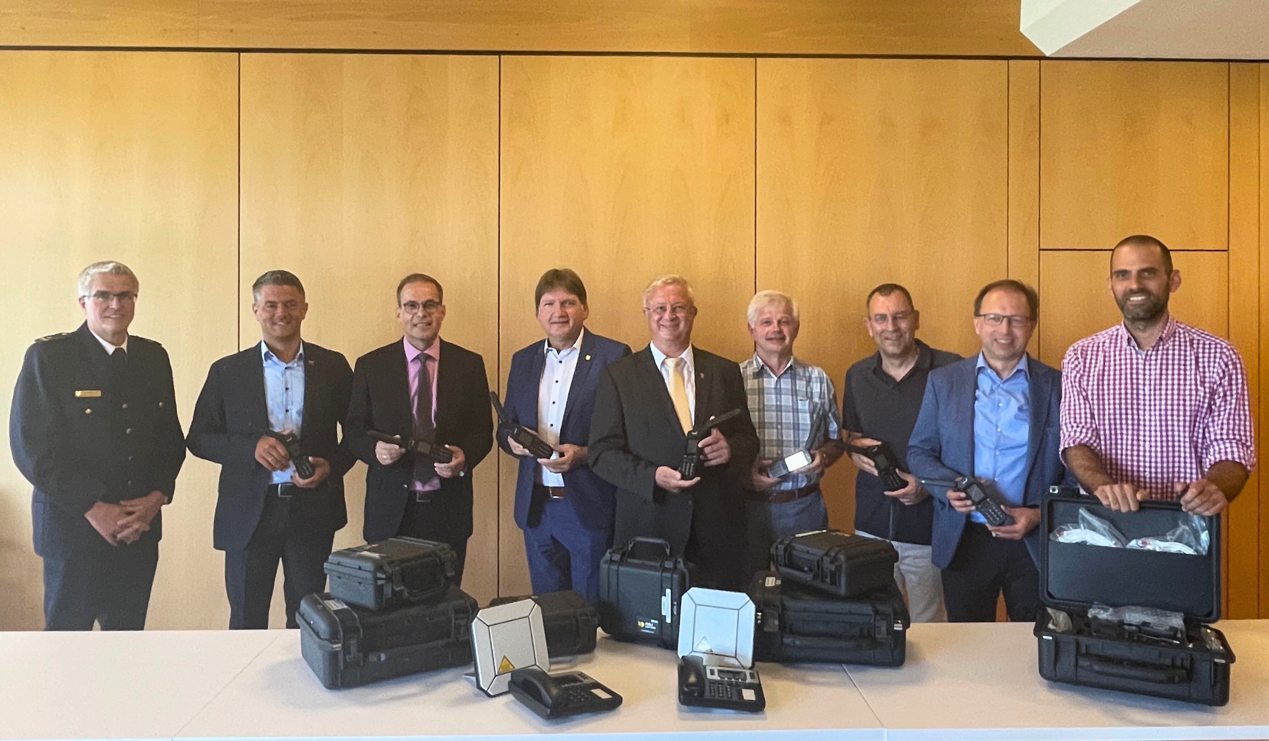 (v. l.) BKI Michael Matthes, Bürgermeister Stef-fen Jung sowie die Verbandsbürgermeister Steffen Unger, Gerd Rocker, Walter Wagner, Ralph Bothe, Markus Conrad und Maximilian Abstein präsentieren zusammen mit Landrat Heiko Sippel (Mitte) die neuen Satellitentelefone, die im Kata-strophenfall im Einsatz sind.