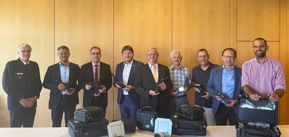 (v. l.) BKI Michael Matthes, Bürgermeister Stef-fen Jung sowie die Verbandsbürgermeister Steffen Unger, Gerd Rocker, Walter Wagner, Ralph Bothe, Markus Conrad und Maximilian Abstein präsentieren zusammen mit Landrat Heiko Sippel (Mitte) die neuen Satellitentelefone, die im Kata-strophenfall im Einsatz sind.