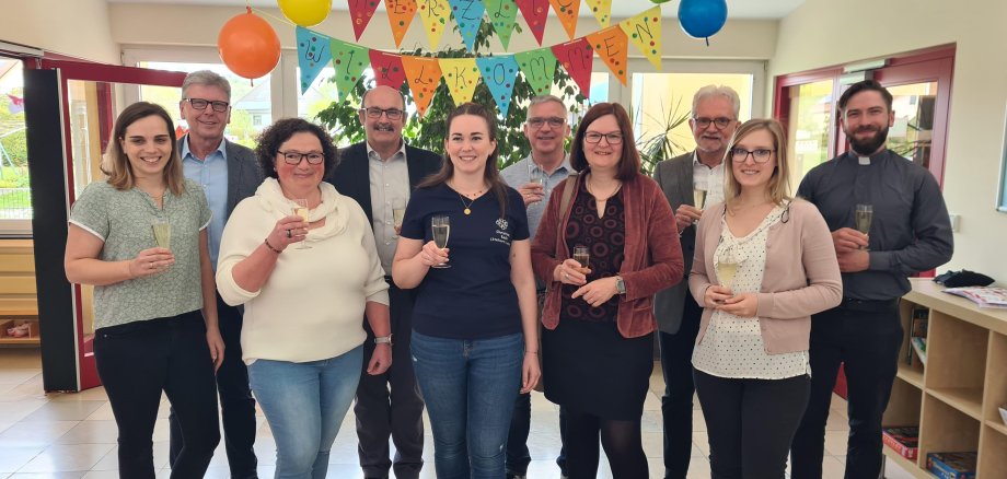 Ein Prosit auf den Anbau zur Kita Sonnenschein. Es freuen sich, vorne von rechts: Vanessa Schmitt (Jugendamt Kreisverwaltung Alzey-Worms), Anke Scherzer (ehemalige Leiterin der Kita), Christine Koch (kommissarische Leiterin), Susanne Schopp (neue Kita-Leitung ab Mai) und Carina Jacobs (Vorsitzende des Elternausschuss) zusammen mit (hinten von rechts) Pfarrer Johannes Mankel, Bauleiter Karl-Heinz Brück, Thorsten Jahn (Ortsbürgermeister Stein-Bockenheim), Jochen Emrich (Ortsbürgermeister Wonsheim) und Alfons Schnabel (1. Beigeordneter der Verbandsgemeinde Wöllstein).